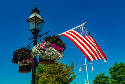 Low angle view of flags against clear blue sky