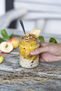 Cropped image of hand holding jar with apple porridge on table 