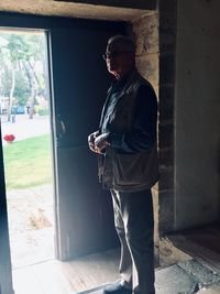 Man holding camera while standing by window