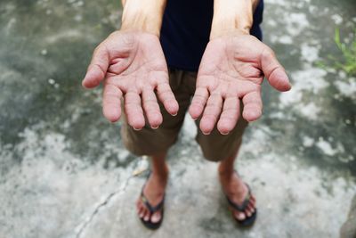 Low section of man gesturing while standing on footpath