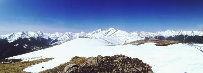 Scenic view of snowcapped mountains against blue sky