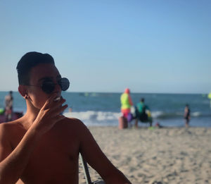Man wearing sunglasses on beach against sky