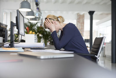 Businesswoman working in office, being stressed out