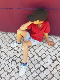 Full length of boy sitting on cobblestone