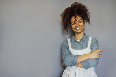 Portrait of young woman standing against wall