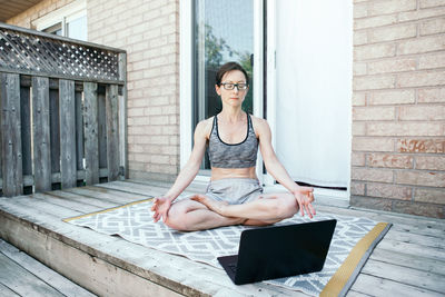 Middle age caucasian woman practising yoga on backyard online. video sport workout on internet. 