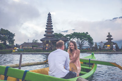 Couple in outrigger boat on lake against temple