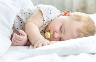 Side view of baby girl sleeping on bed at home