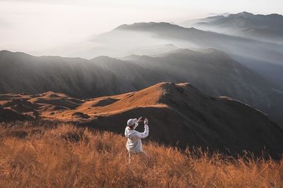 Rear view of man on mountain against sky