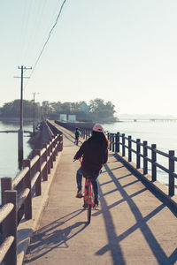 Full length rear view of woman on sea against clear sky