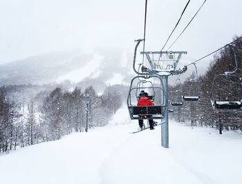 Overhead cable car on snow covered mountain against sky