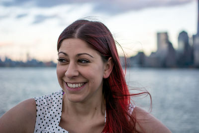 Portrait of smiling young woman against sea