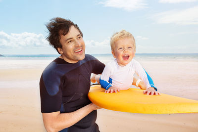 Portrait of smiling boy sitting at beach against sky