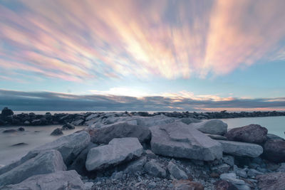 Rocks on beach against sky during sunset