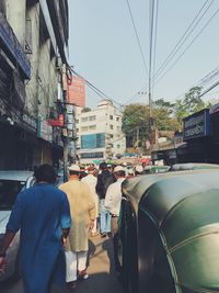 Rear view of man traveling in city against sky