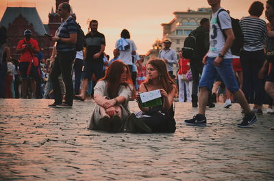 People sitting on street in city at sunset