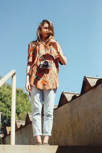 Low angle view of girl standing against clear blue sky