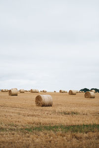 Hay bales on field against sky