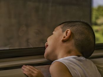 Close-up of smiling boy looking through window