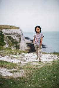 Portrait of boy standing on cliff against sky
