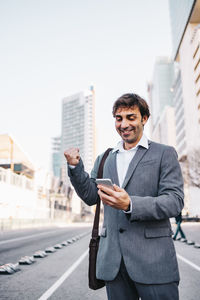 Low angle view of businessman using smart phone while standing on road