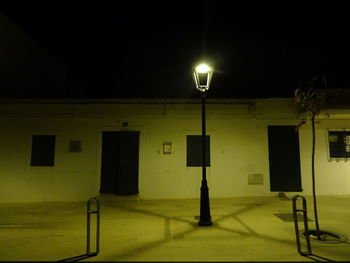Illuminated street light against sky at night