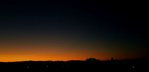 Silhouette landscape against clear sky at sunset