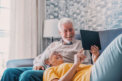 Young woman using digital tablet while sitting on sofa at home