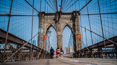 People on suspension bridge in city