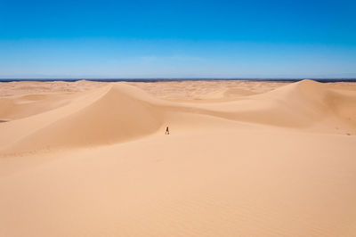 Teenage girl on desert against sky