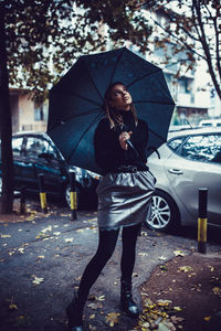 Full length of woman with umbrella standing in rain