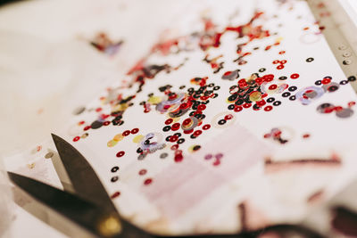 Close-up of sequins with scissor on table