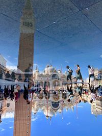 People and st marks campanile reflecting in puddle