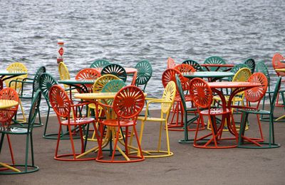 Colorful chairs on walkway against sea