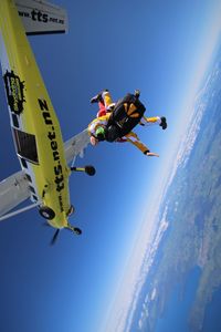 Low angle view of people paragliding against sky