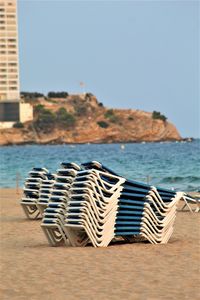 Chairs on beach against clear sky