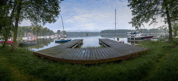 Sailboats moored on lake against sky