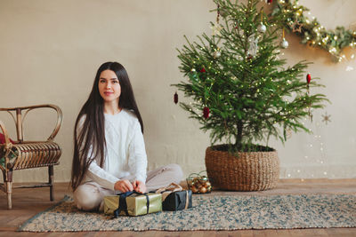 Portrait of beautiful woman sitting against wall