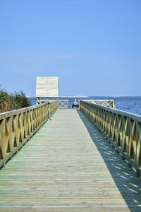 Pier over sea against clear blue sky