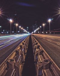 Illuminated railroad tracks against sky at night