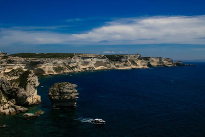 Scenic view of sea by cliff against blue sky