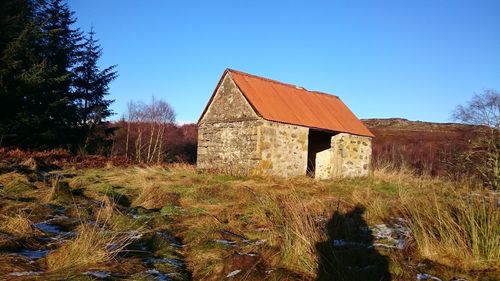 Built structure on landscape against clear blue sky