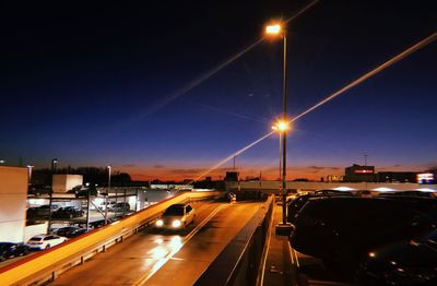 Cars on illuminated road against sky at night
