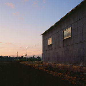 Building on field against sky during sunset