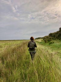 Rear view of man on field against sky