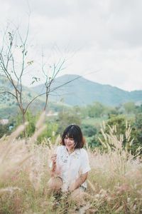 Smiling mature woman crouching on grassy field