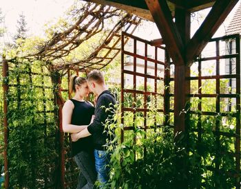 Romantic couple standing by plants at backyard
