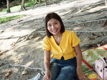 Portrait of smiling young woman sitting on rock