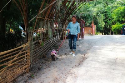 Full length of woman walking with dog on road