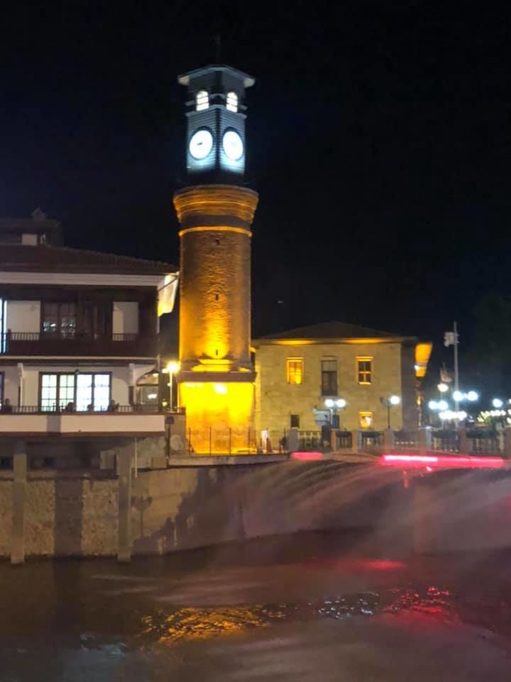 ILLUMINATED STREET LIGHT BY ROAD AGAINST BUILDINGS AT NIGHT